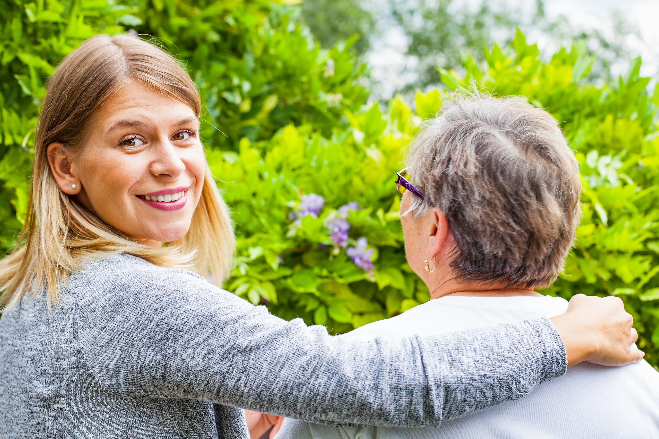 Picture of a senior with her caregiver in the park, back view