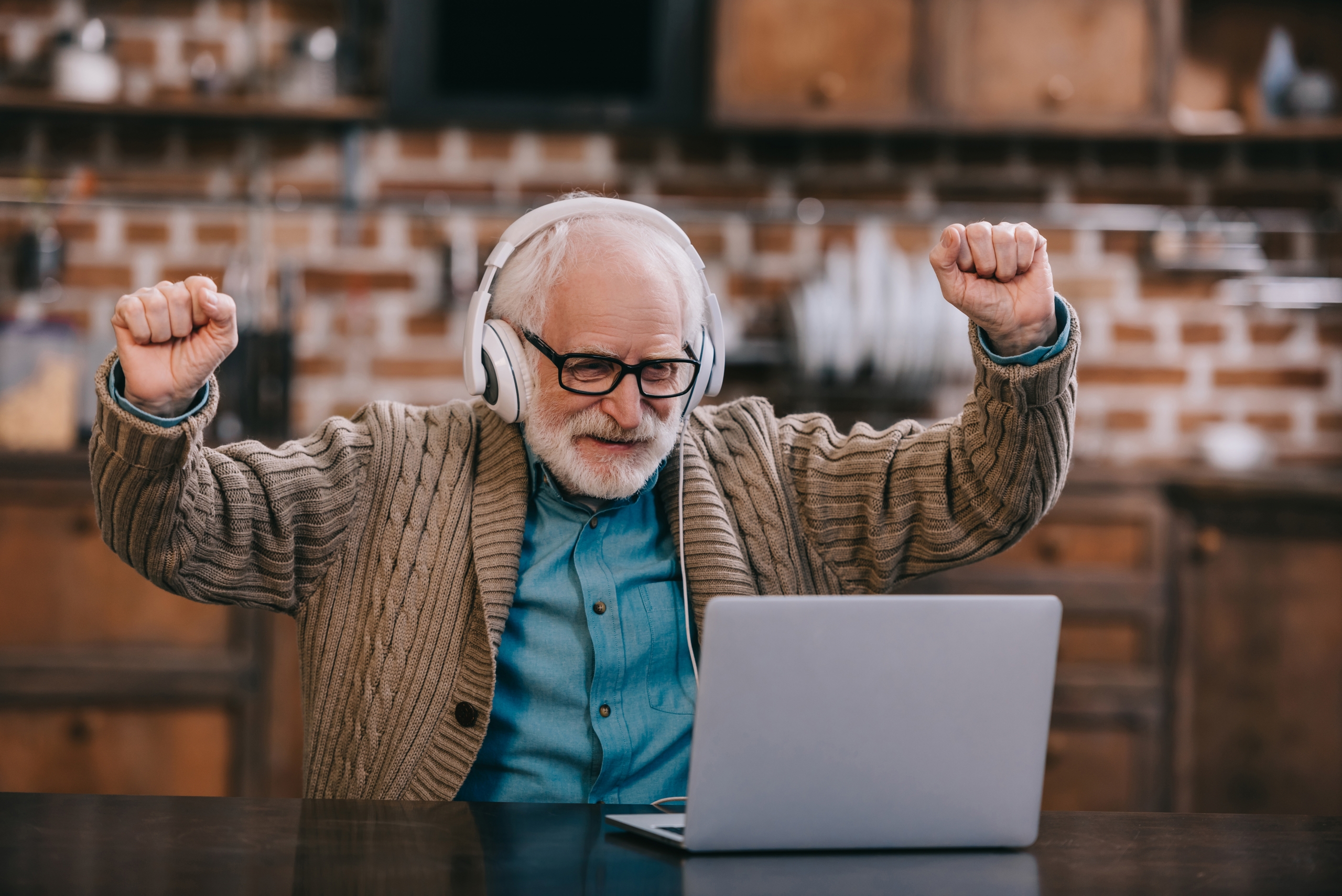 Elder gentleman with headphones at laptop