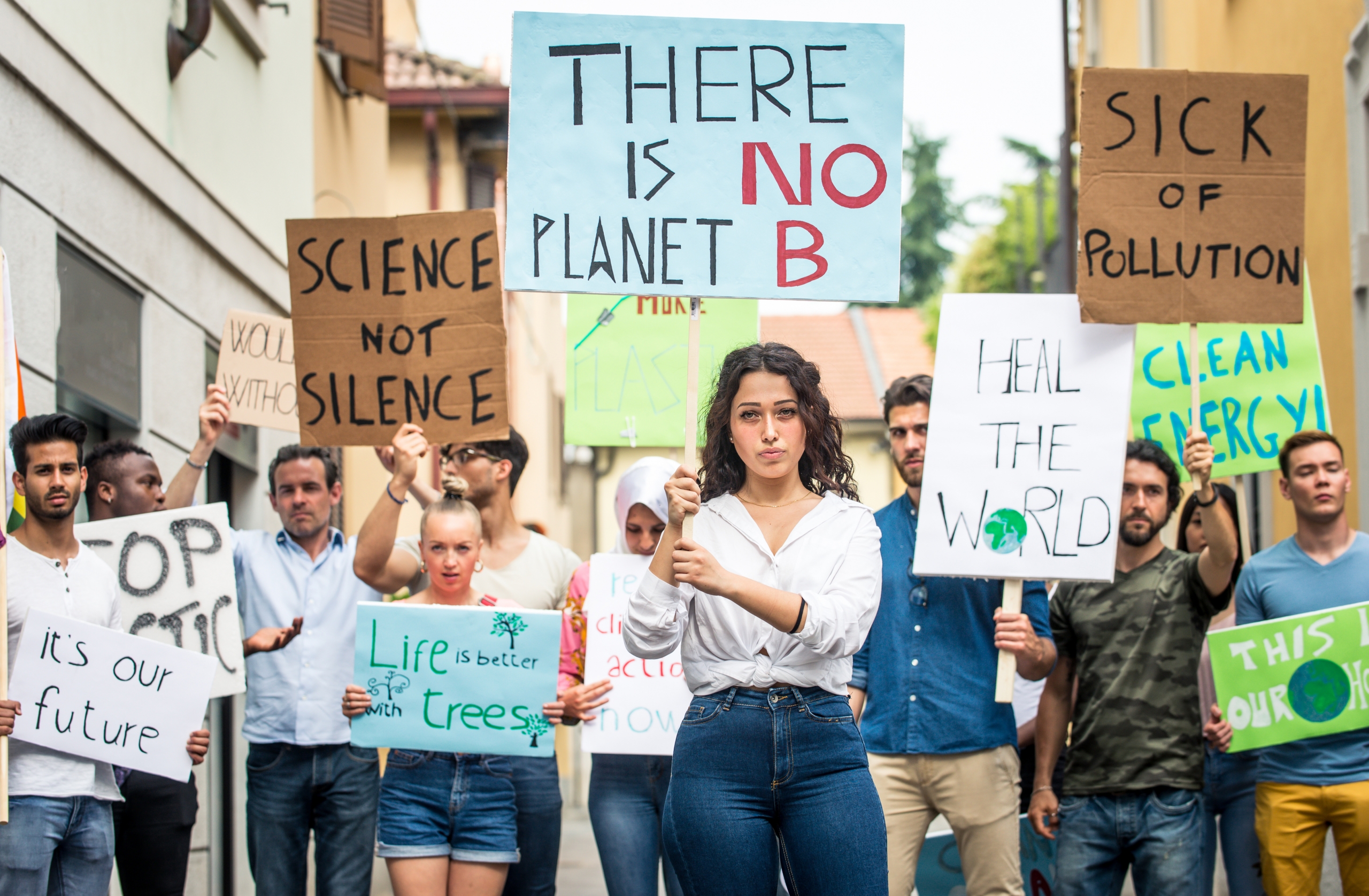 Public demonstration on the street against global warming and pollution. Group of multiethnic people making protest about climate change and plastic problems in the oceans