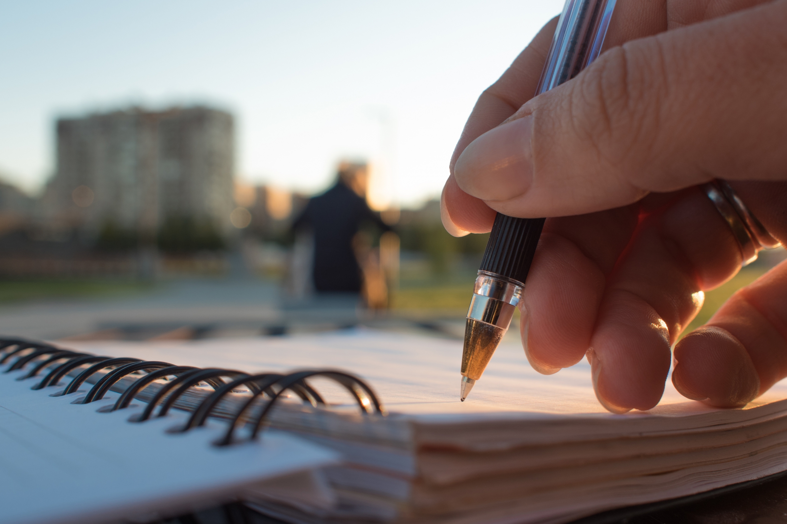 Close-up, writing in journal: Hand holding pen, writing in journal