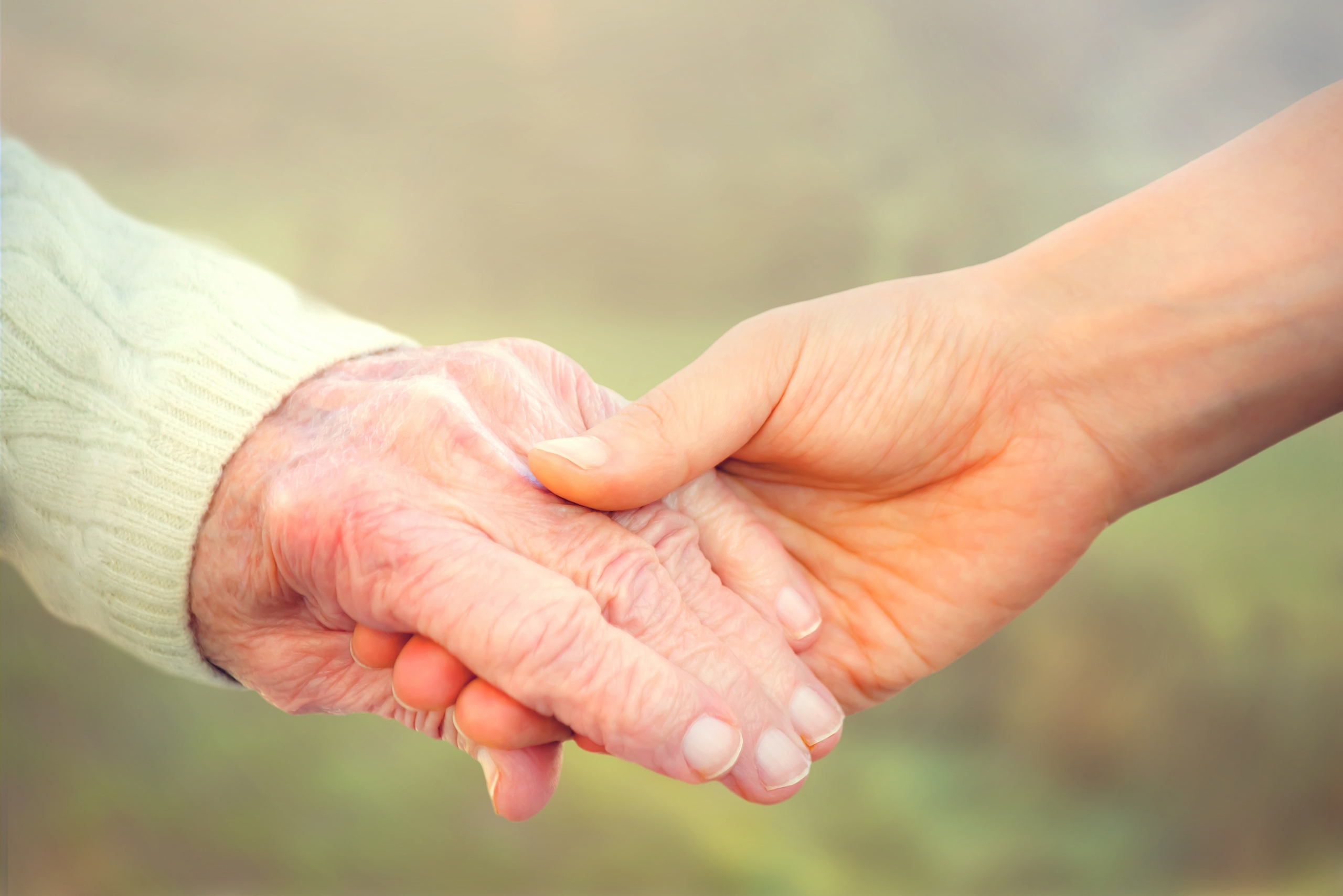 Elderly woman holding hands with caregiver