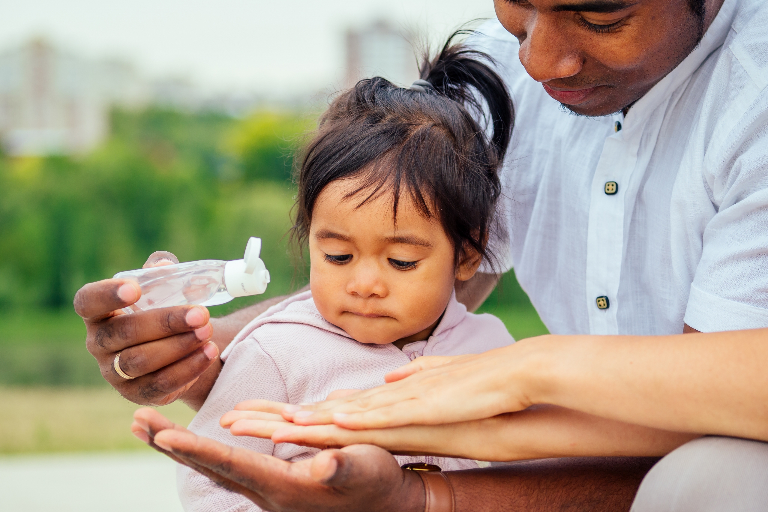 Parents and child applying hand sanitizer