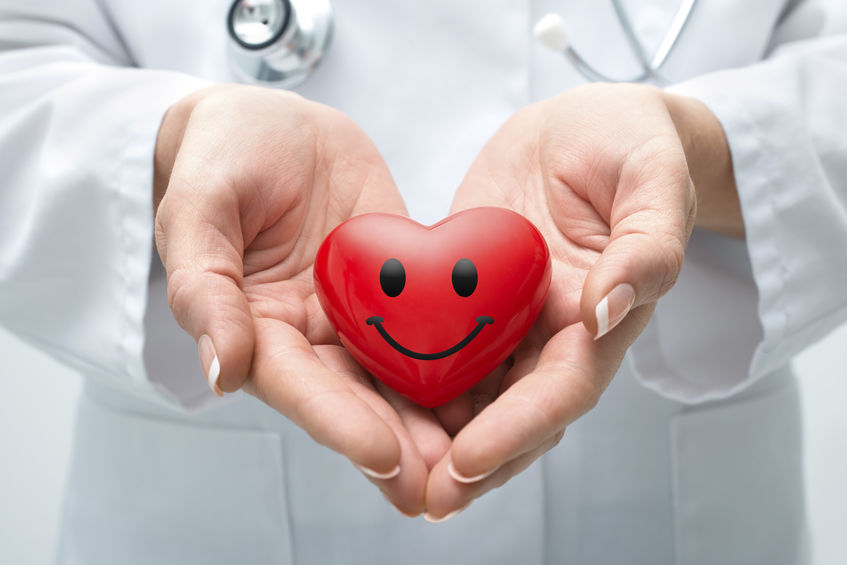 Female doctor with the stethoscope holding smiling heart