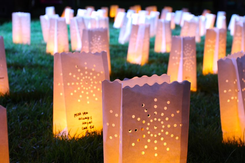 a group of glowing candle bags on the grass for COVID Memorial