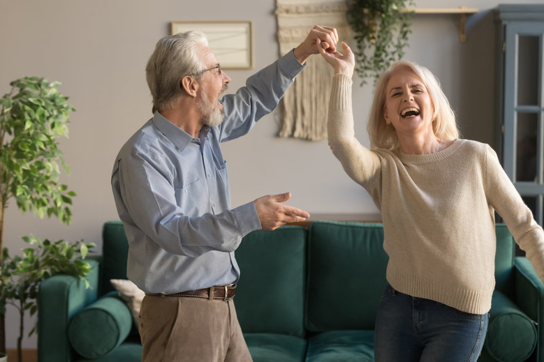 Joyful couple dancing and laughing in their home